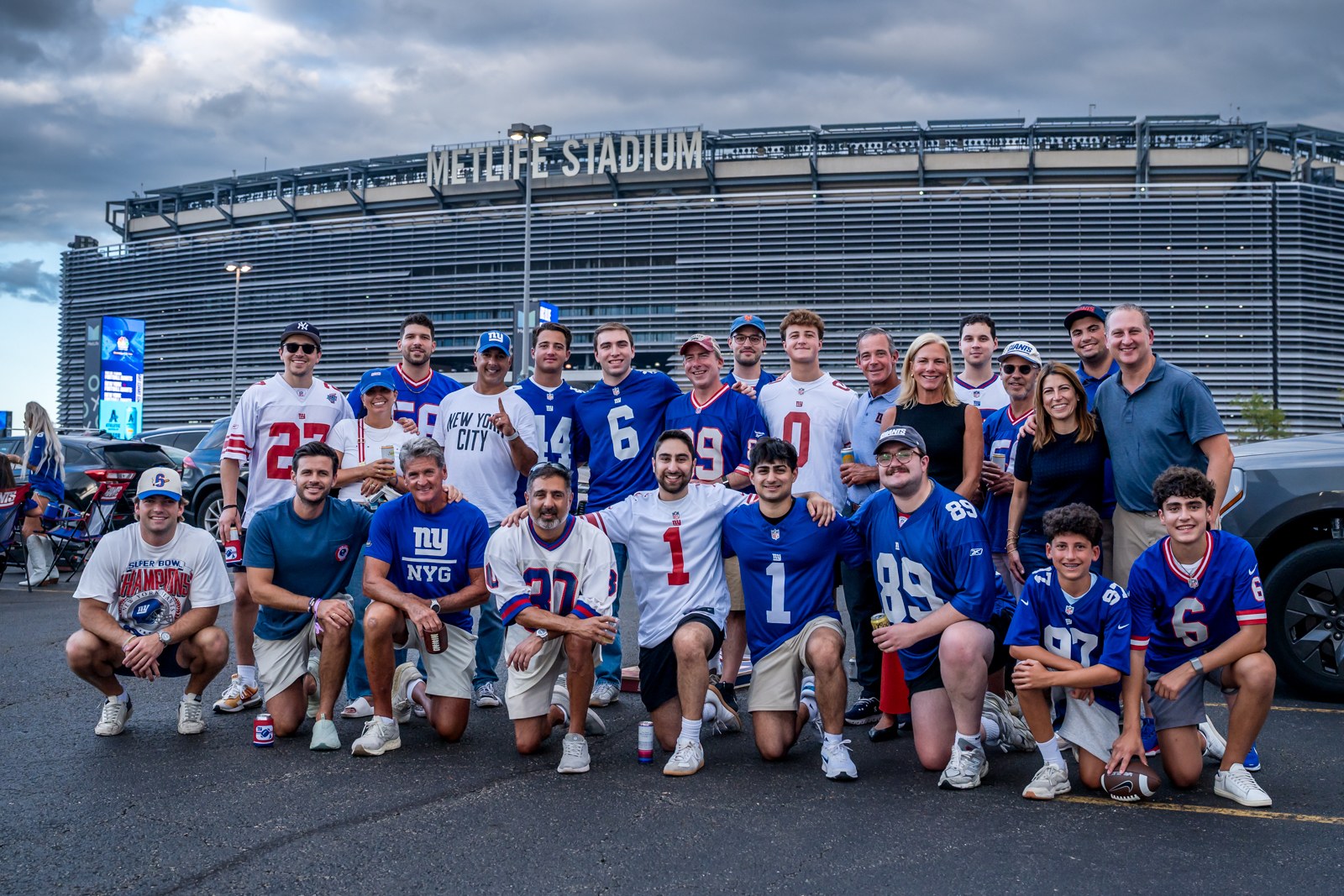 Giants fans in blue jerseys posing together outside MetLife Stadium.