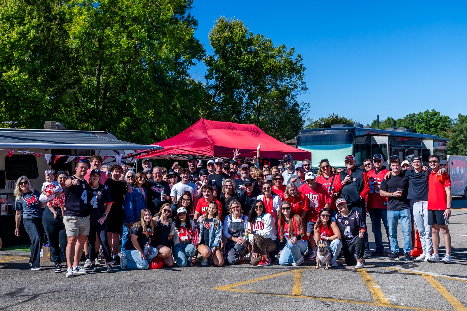 Miami OH tailgate group with adults and children beneath red tents.